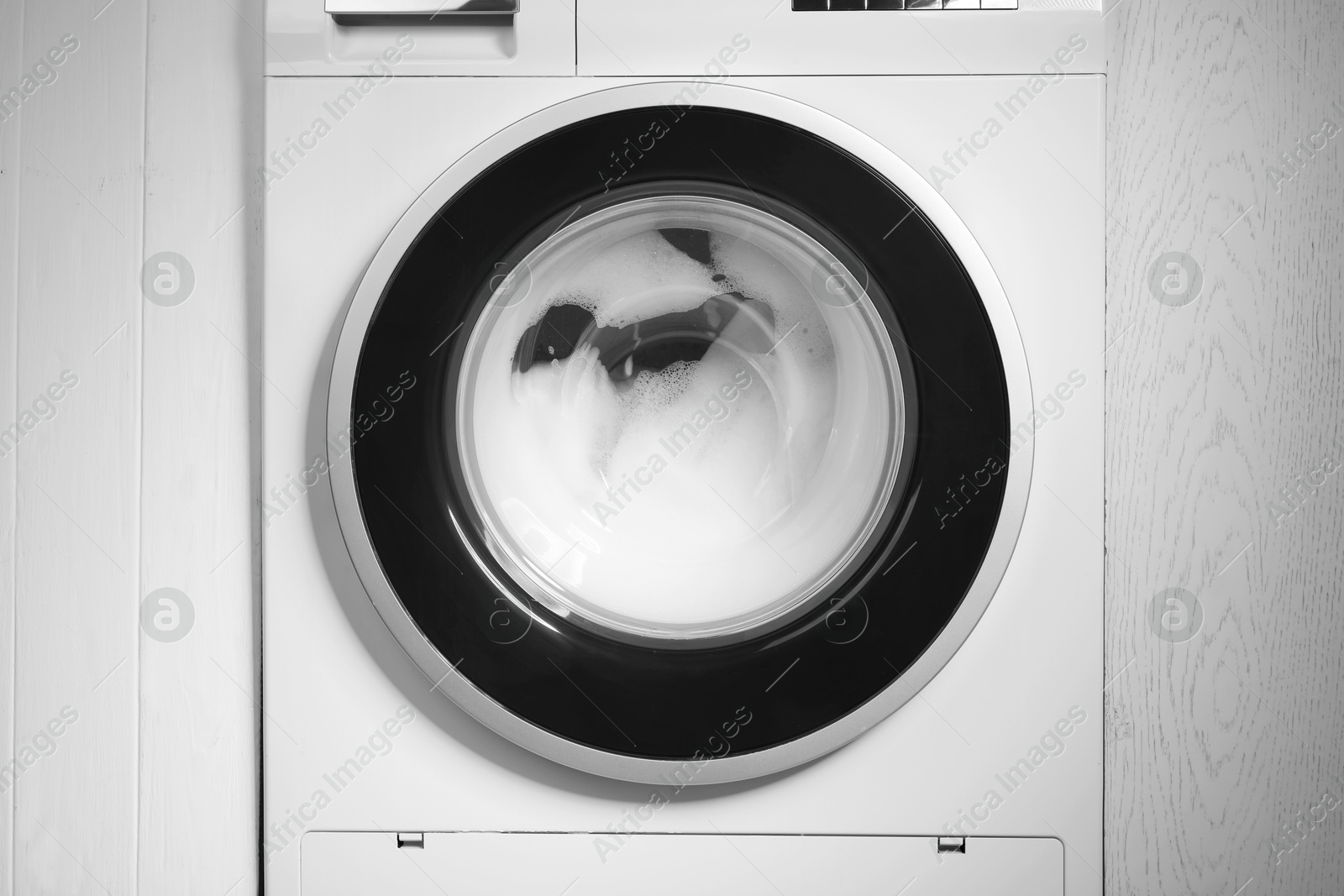 Photo of Washing machine with suds as background, closeup