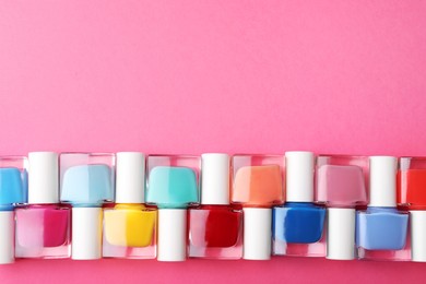 Photo of Set of different nail polishes on pink background, flat lay. Space for text