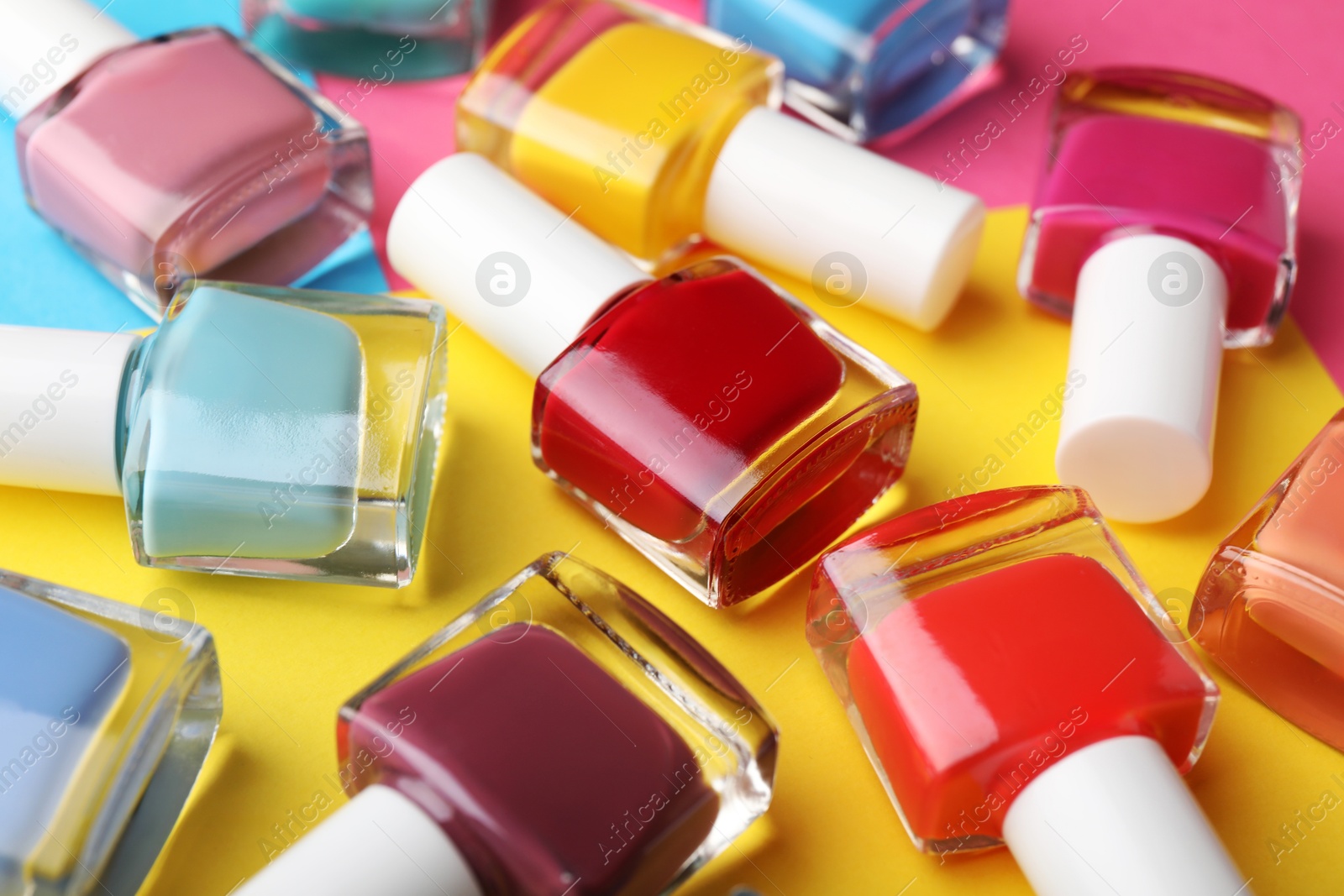 Photo of Set of different nail polishes in bottles on color background, closeup