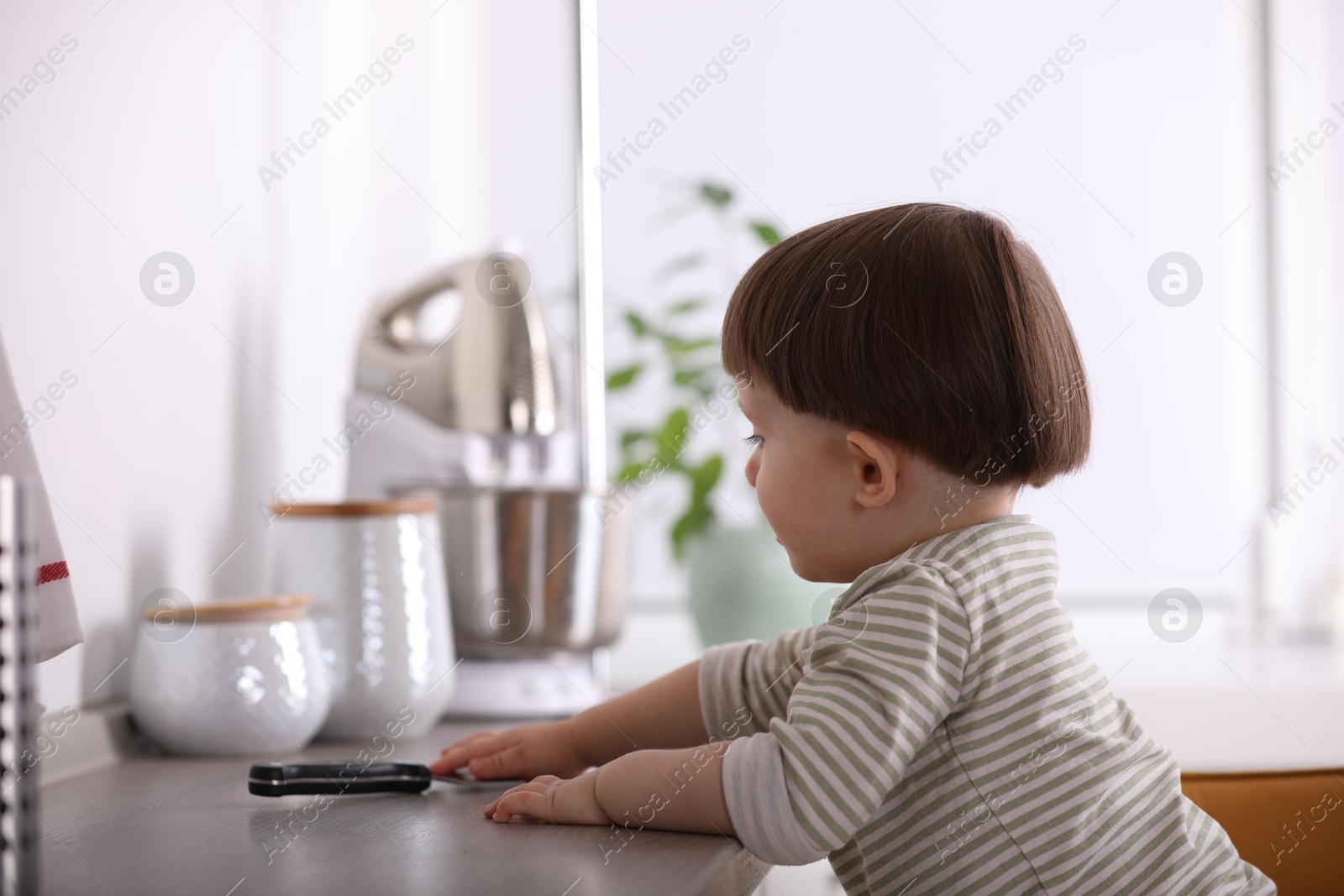 Photo of Little boy reaching towards knife on kitchen counter. Dangerous situation