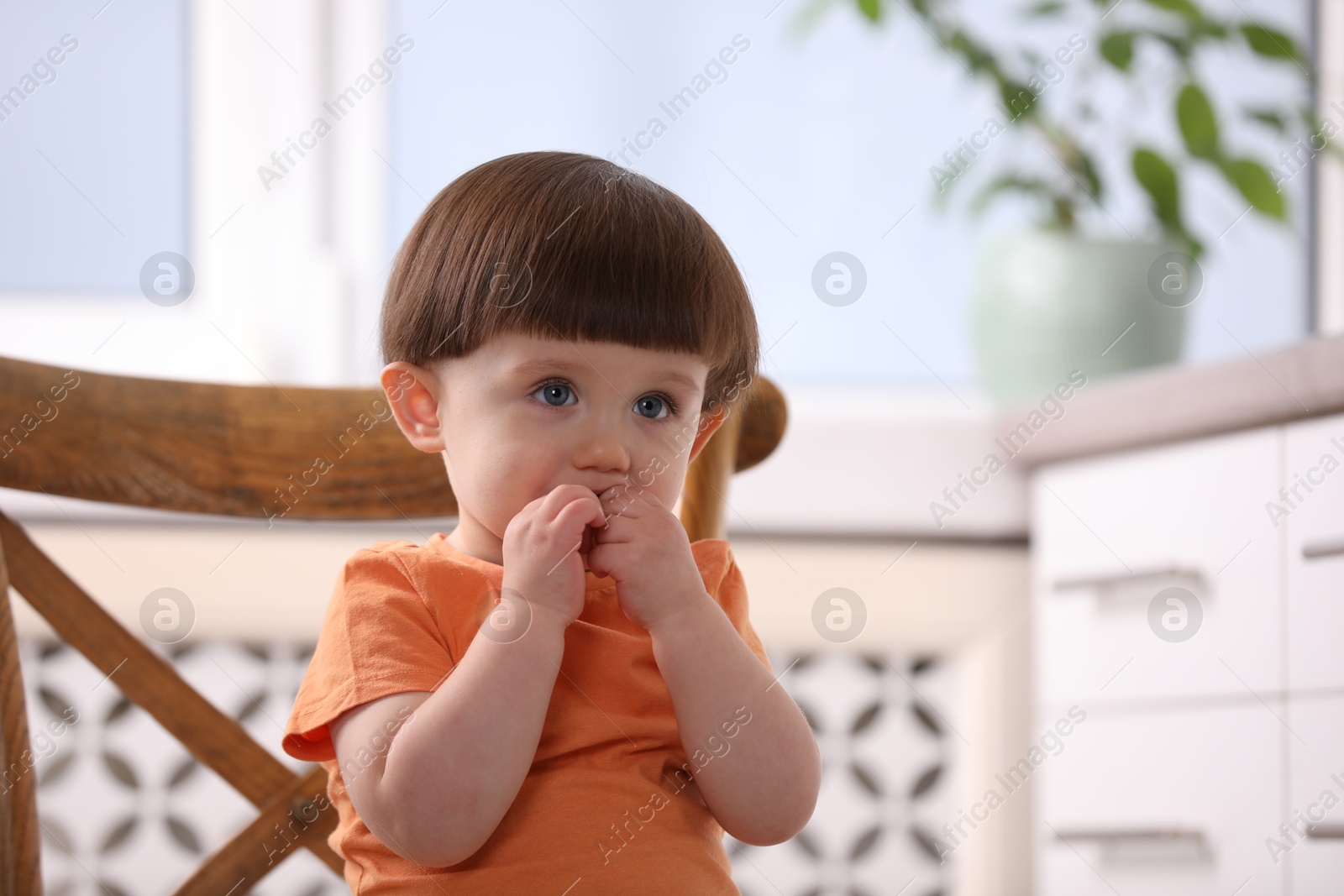 Photo of Little boy playing on chair in kitchen. Dangerous situation