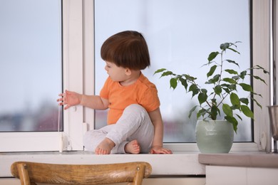 Photo of Little boy near window on windowsill. Dangerous situation