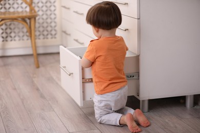 Photo of Little boy playing with kitchen appliances indoors. Dangerous situation