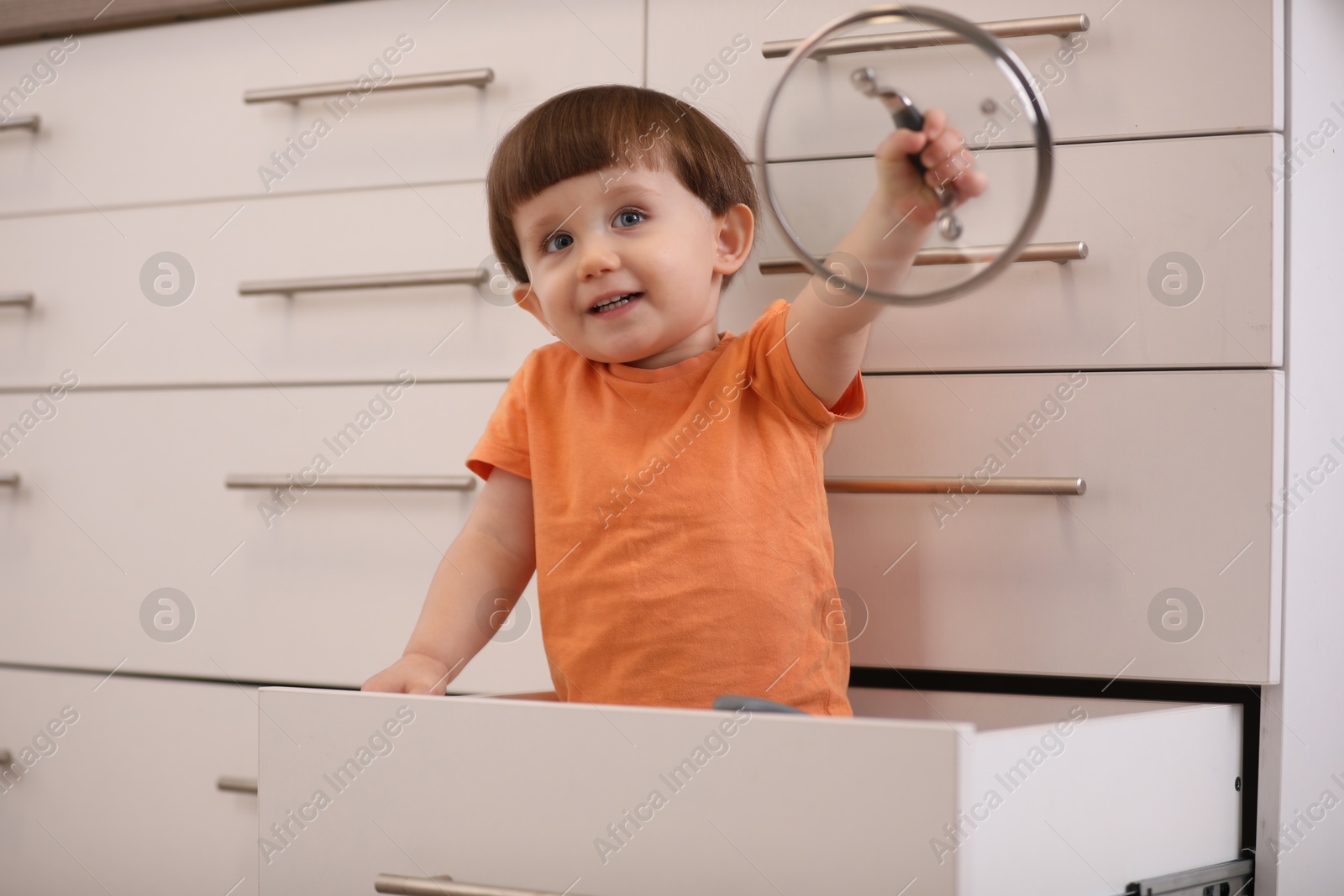 Photo of Little boy playing with kitchen appliances indoors. Dangerous situation