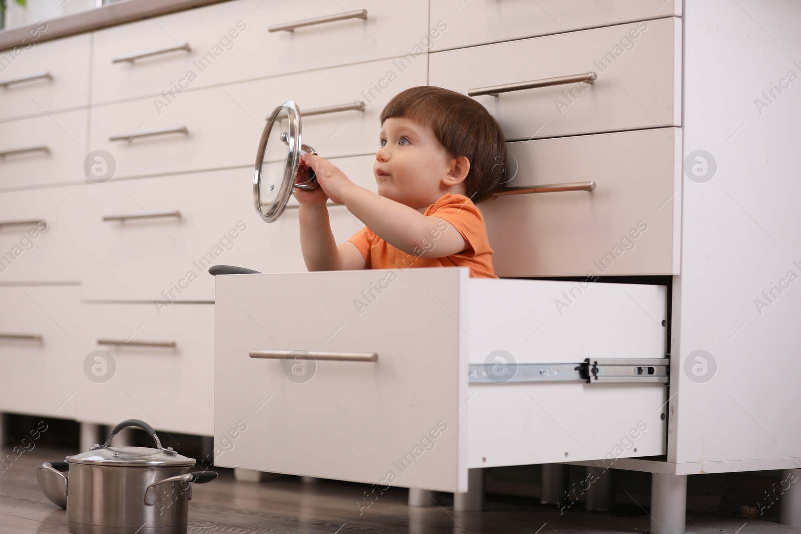 Photo of Little boy playing with kitchen appliances indoors. Dangerous situation