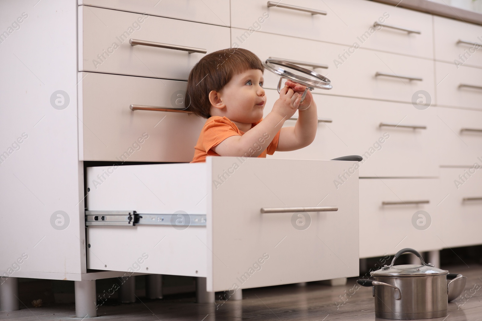 Photo of Little boy playing with kitchen appliances indoors. Dangerous situation