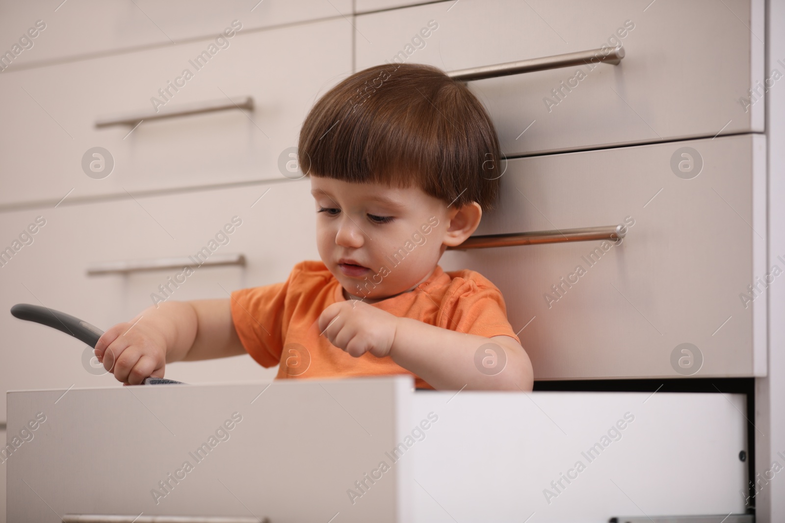 Photo of Little boy playing with kitchen appliances indoors. Dangerous situation