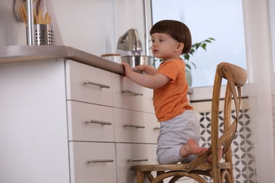 Photo of Little boy playing with kitchen appliances indoors. Dangerous situation