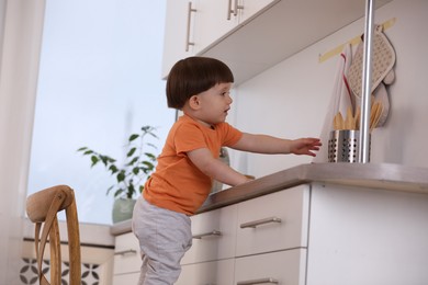 Photo of Little boy playing with kitchen appliances indoors. Dangerous situation