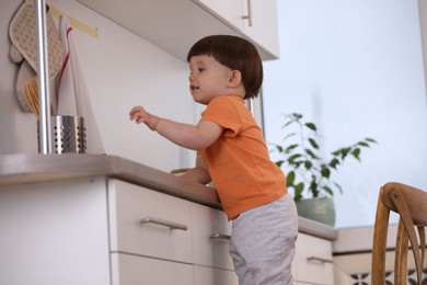 Photo of Little boy playing with kitchen appliances indoors. Dangerous situation