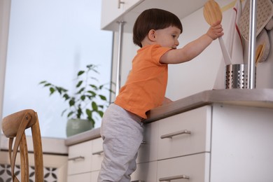 Photo of Little boy playing with kitchen appliances indoors. Dangerous situation