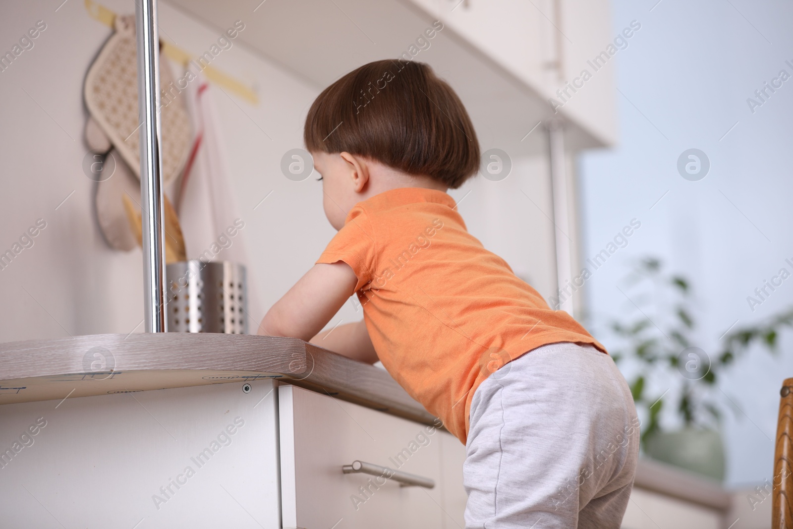 Photo of Little boy playing with kitchen appliances indoors. Dangerous situation