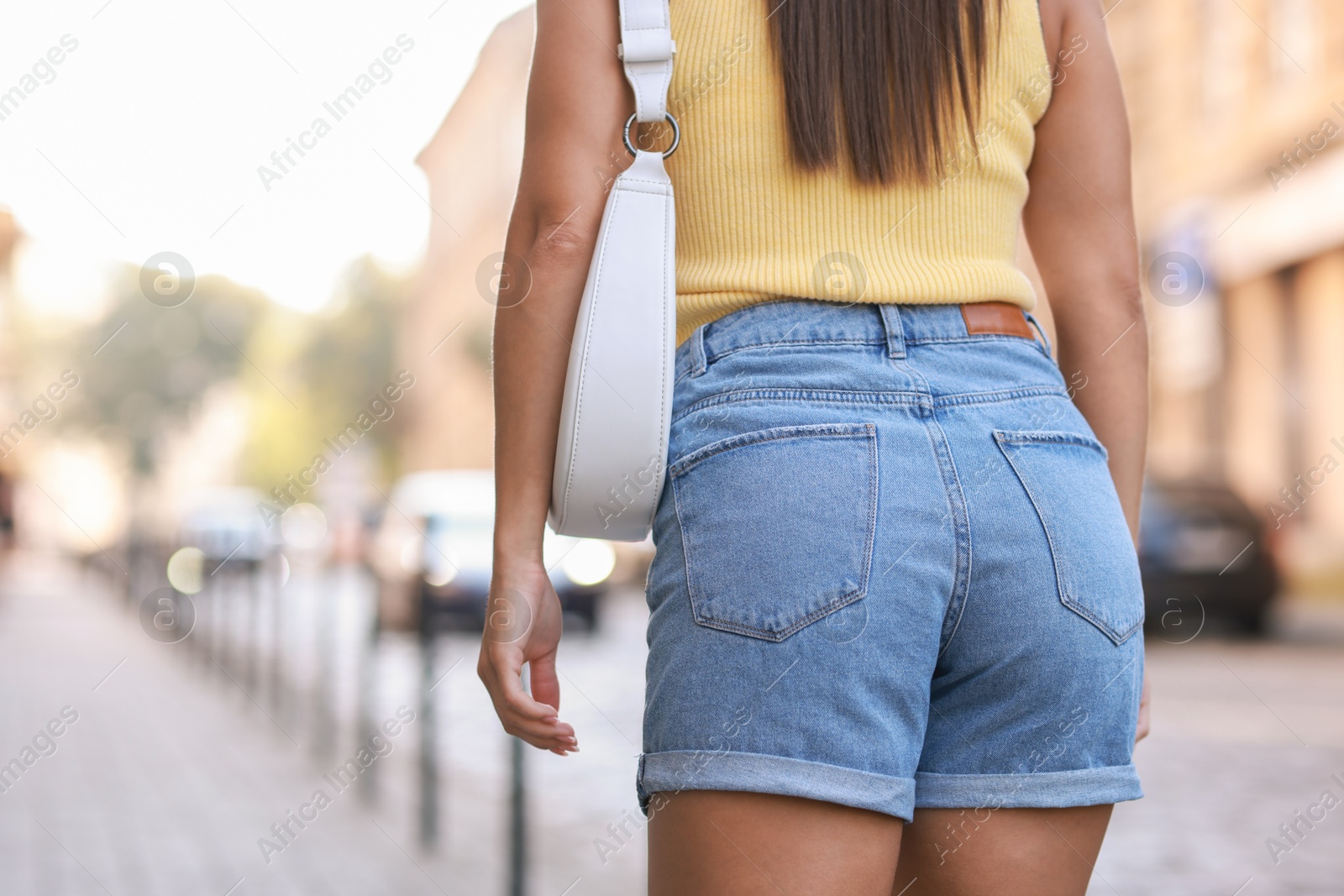 Photo of Woman with white bag wearing stylish denim shorts outdoors, closeup. Space for text