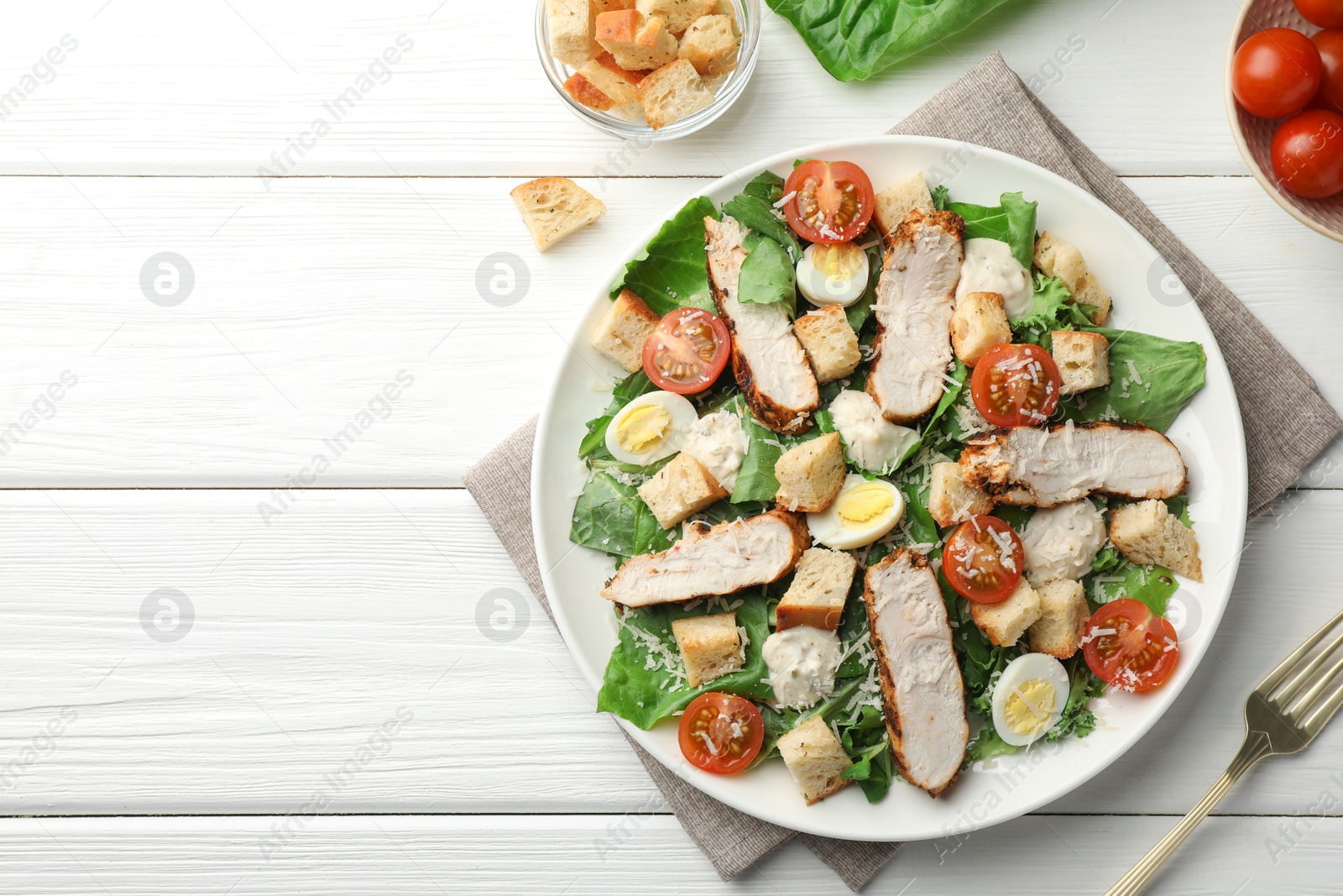 Photo of Tasty Caesar salad with chicken and tomatoes on white wooden table, flat lay. Space for text