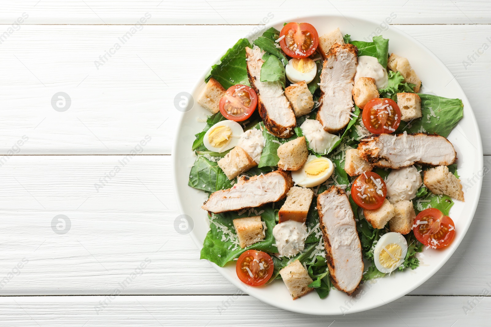 Photo of Tasty Caesar salad with chicken and tomatoes on white wooden table, top view. Space for text