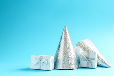 Photo of Gift boxes and party hats on light blue background. Space for text