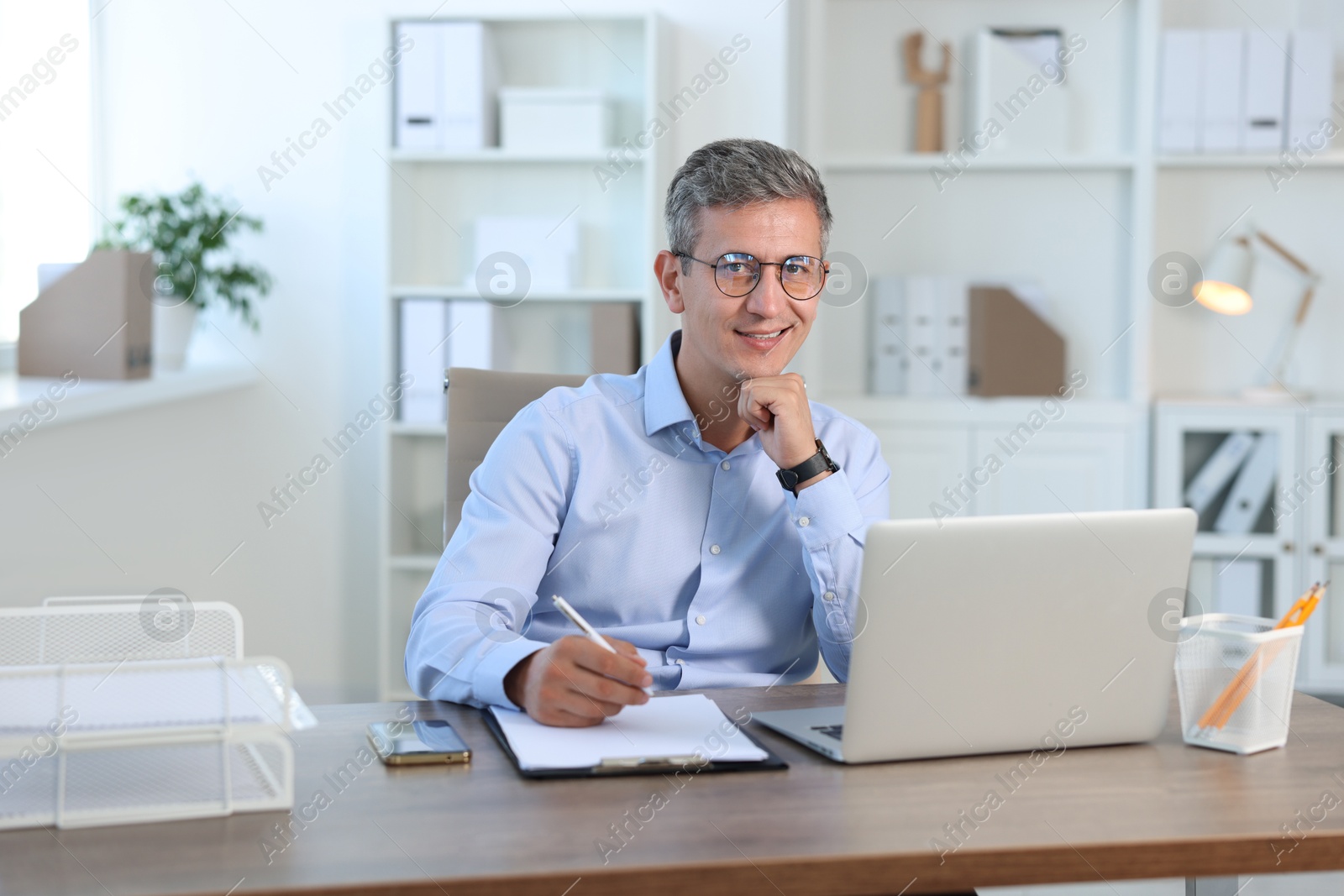 Photo of Portrait of smiling middle aged man at table in office