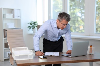 Middle aged man working with laptop in office