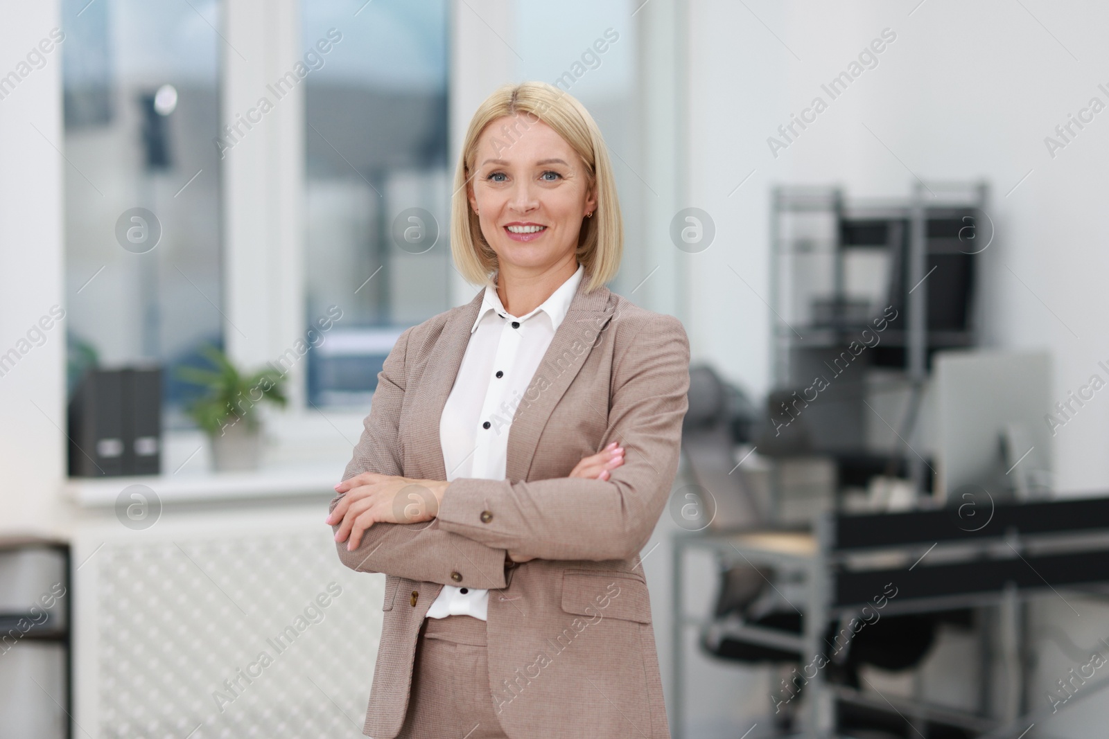 Photo of Portrait of smiling middle aged woman with crossed arms in office