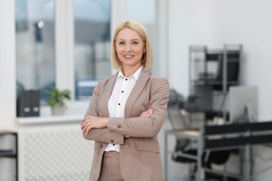 Photo of Portrait of smiling middle aged woman with crossed arms in office