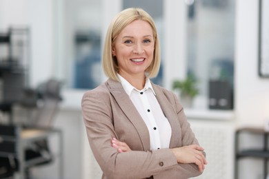 Photo of Portrait of smiling middle aged woman with crossed arms in office