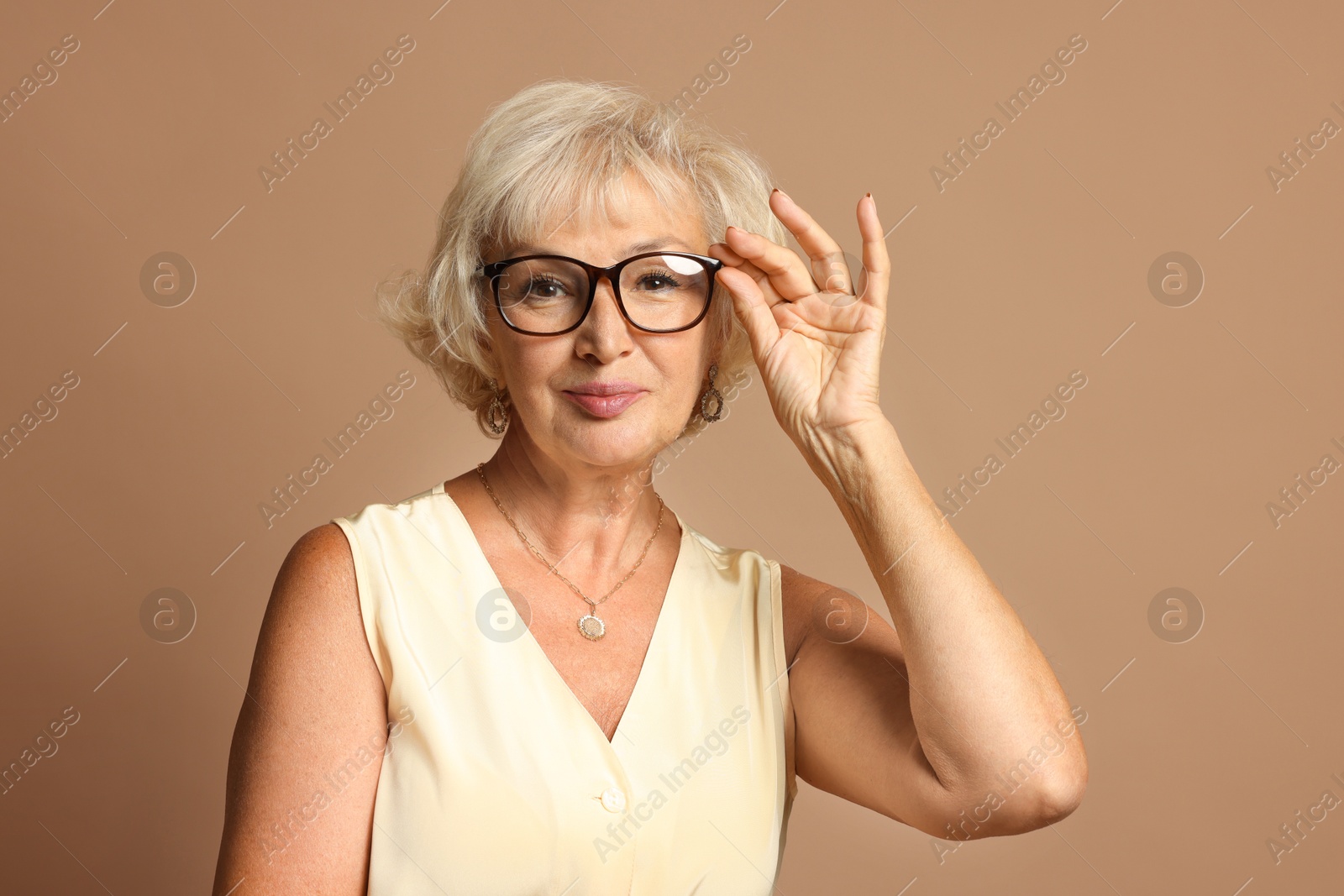 Photo of Portrait of beautiful senior woman on light brown background