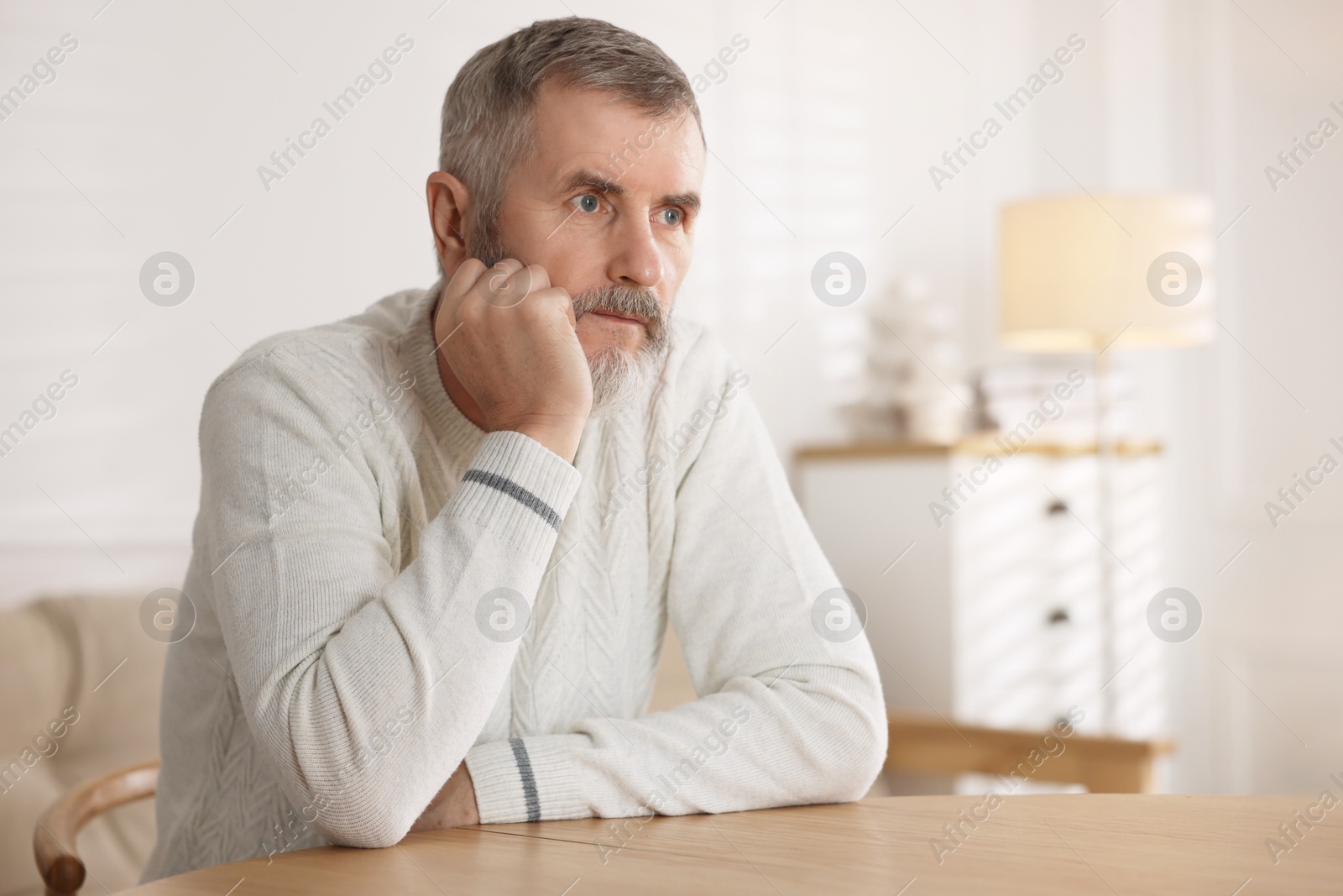 Photo of Senior man at table indoors, space for text