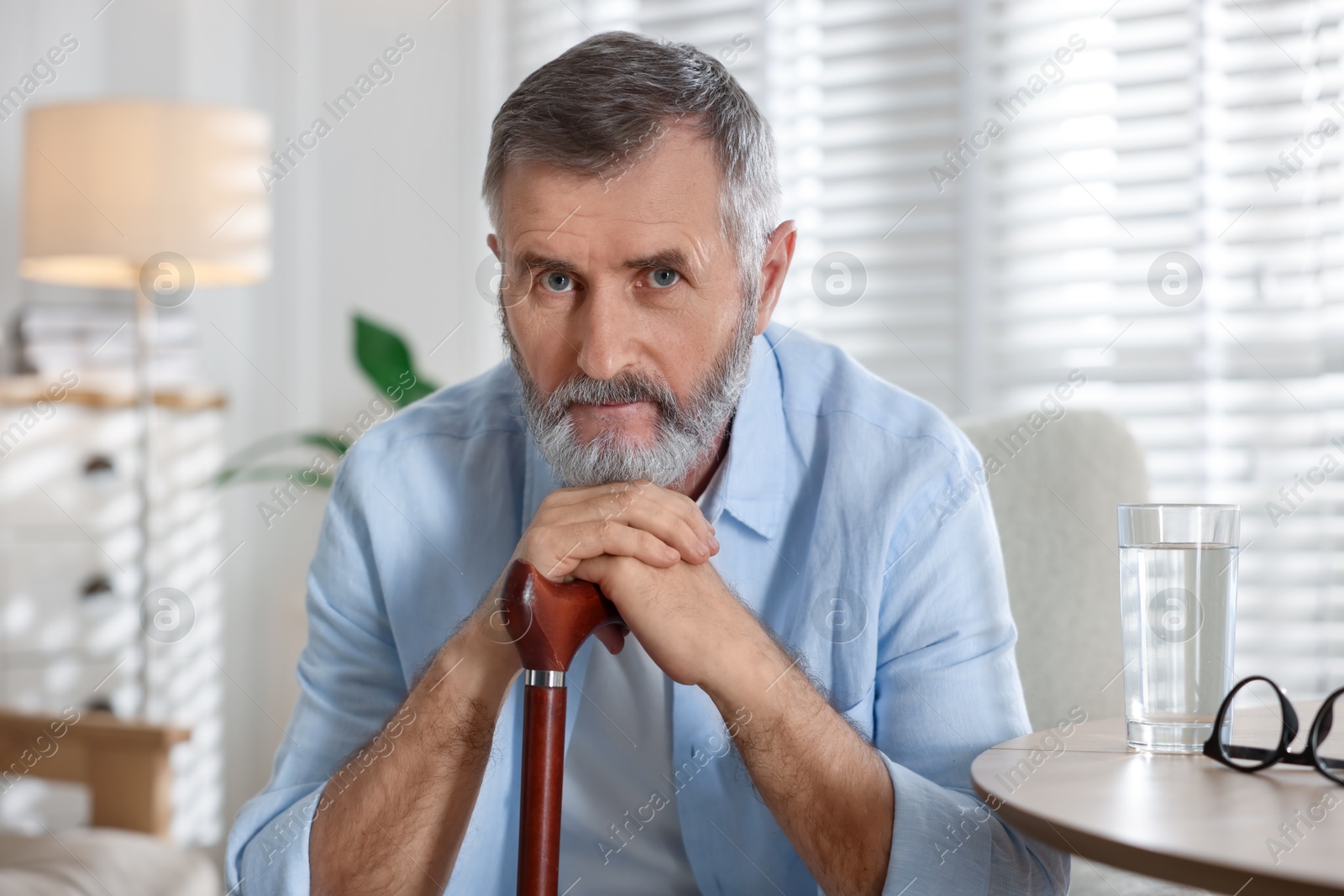 Photo of Senior man with walking cane at home