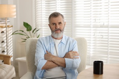 Photo of Portrait of senior man in armchair at home