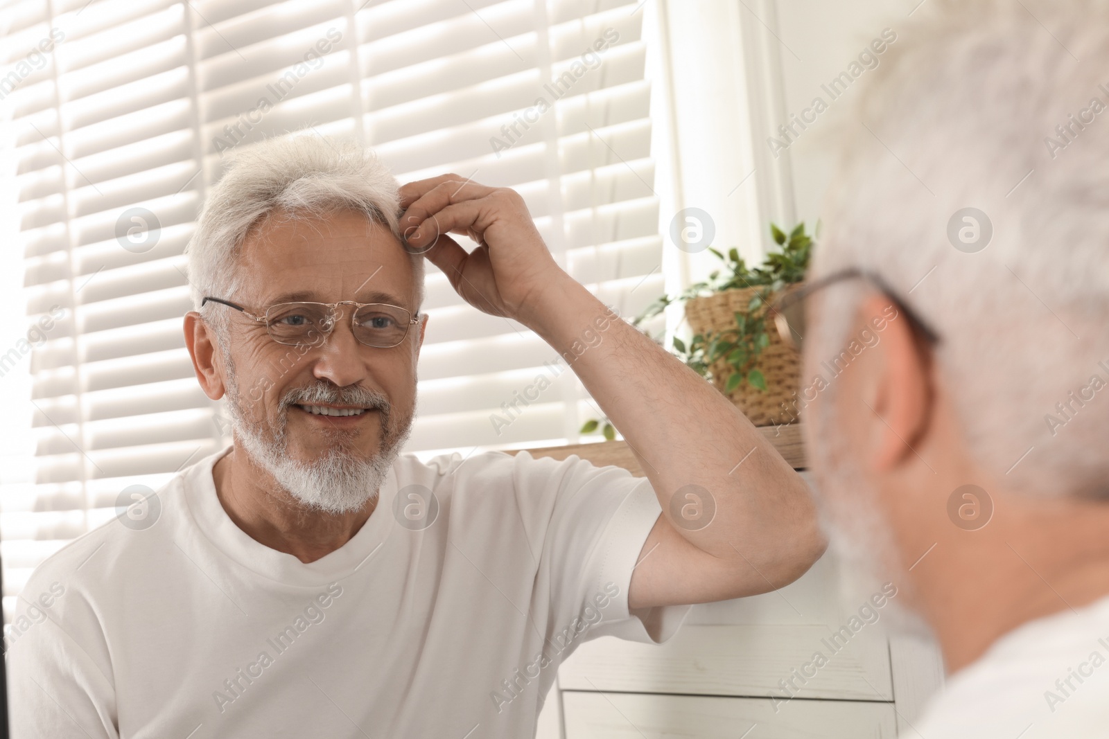 Photo of Senior man looking in mirror at home