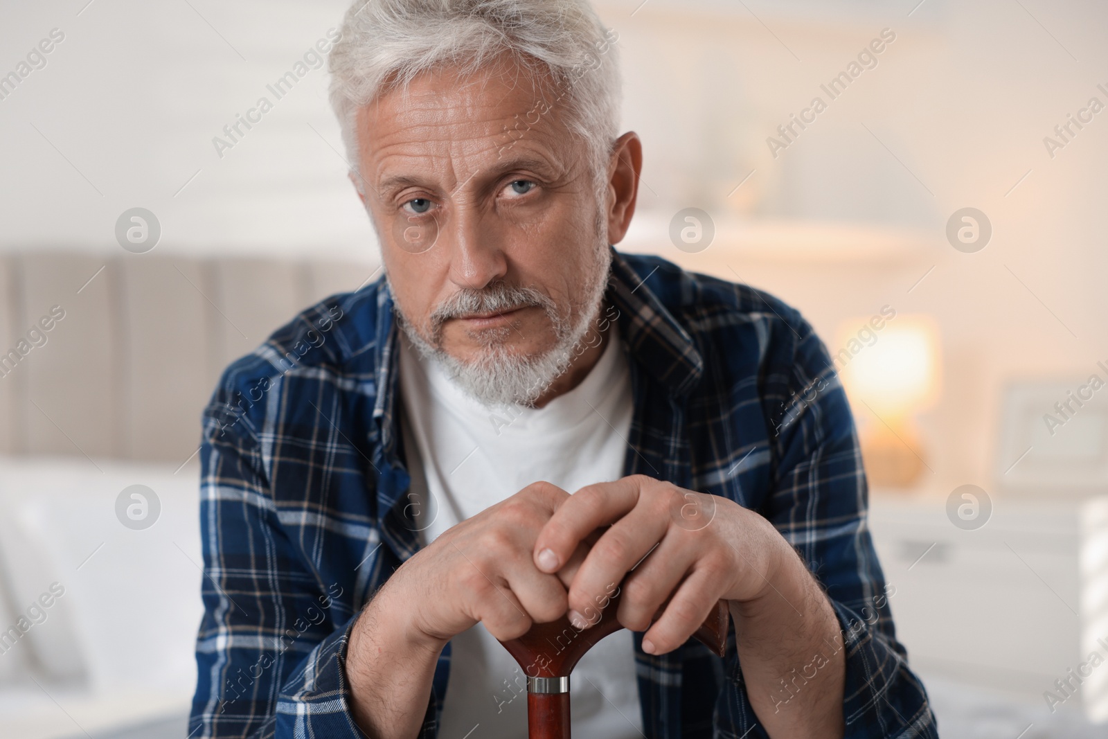 Photo of Senior man with walking cane at home