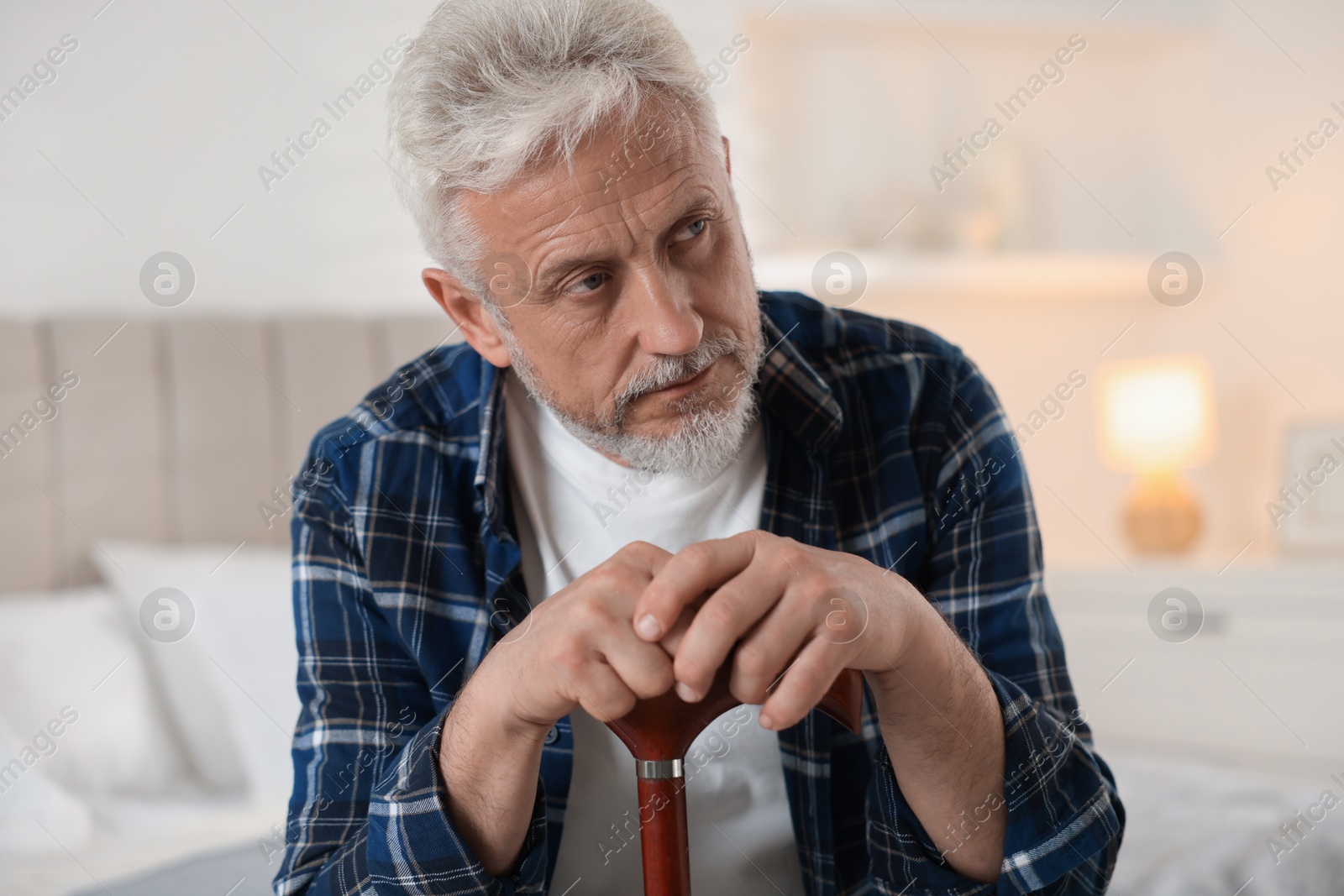 Photo of Senior man with walking cane at home