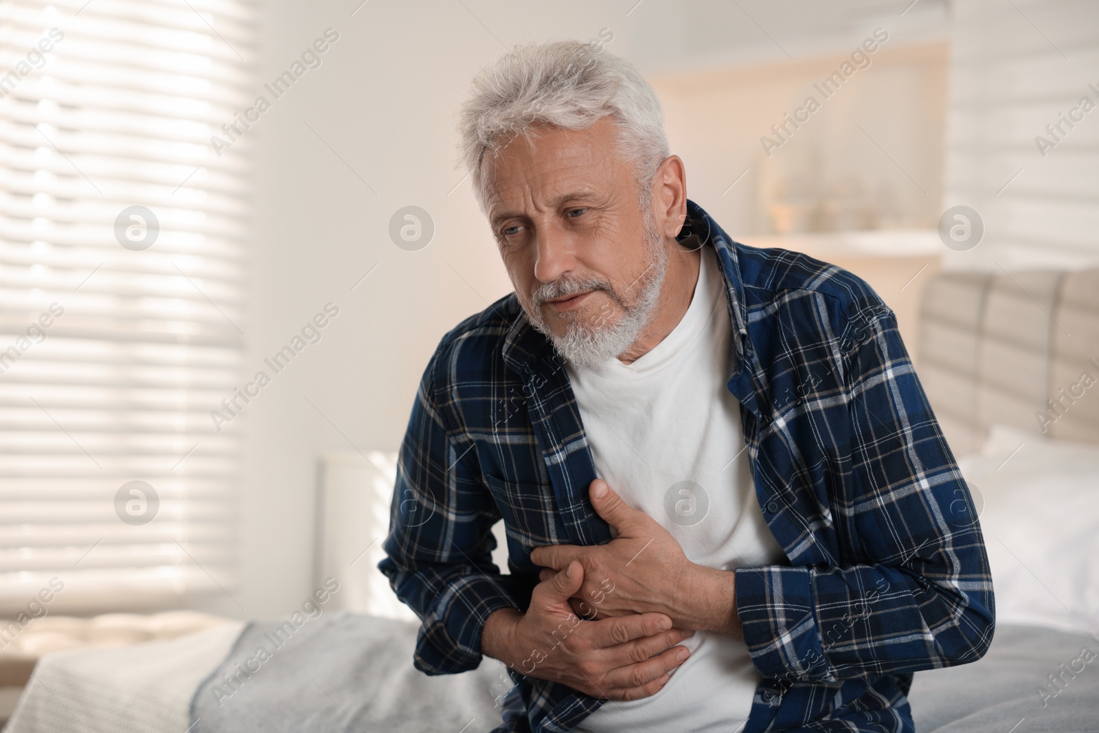 Photo of Senior man suffering from pain in chest at home