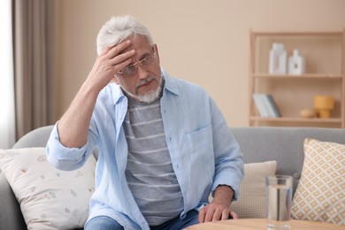 Photo of Senior man suffering from headache at home