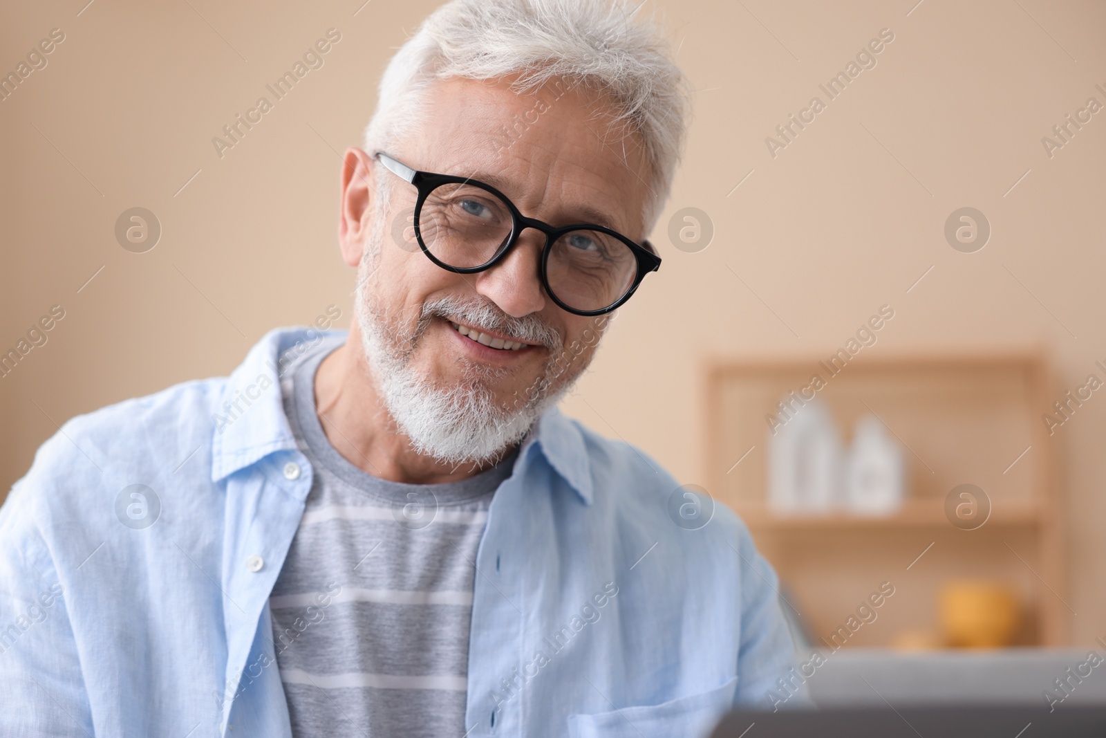 Photo of Happy senior man using laptop at home