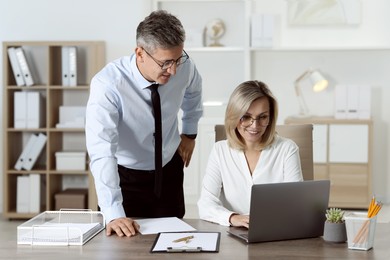 Photo of Middle aged employees working together in office