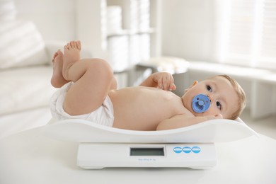 Photo of Cute little child lying on scales in clinic. Checking baby's health