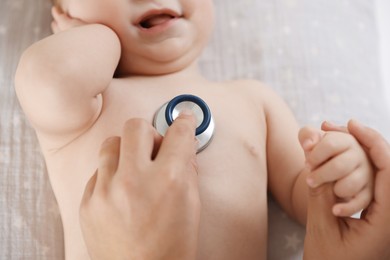 Photo of Pediatrician examining little child with stethoscope in clinic, closeup. Checking baby's health