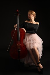 Photo of Beautiful young woman with cello on black background