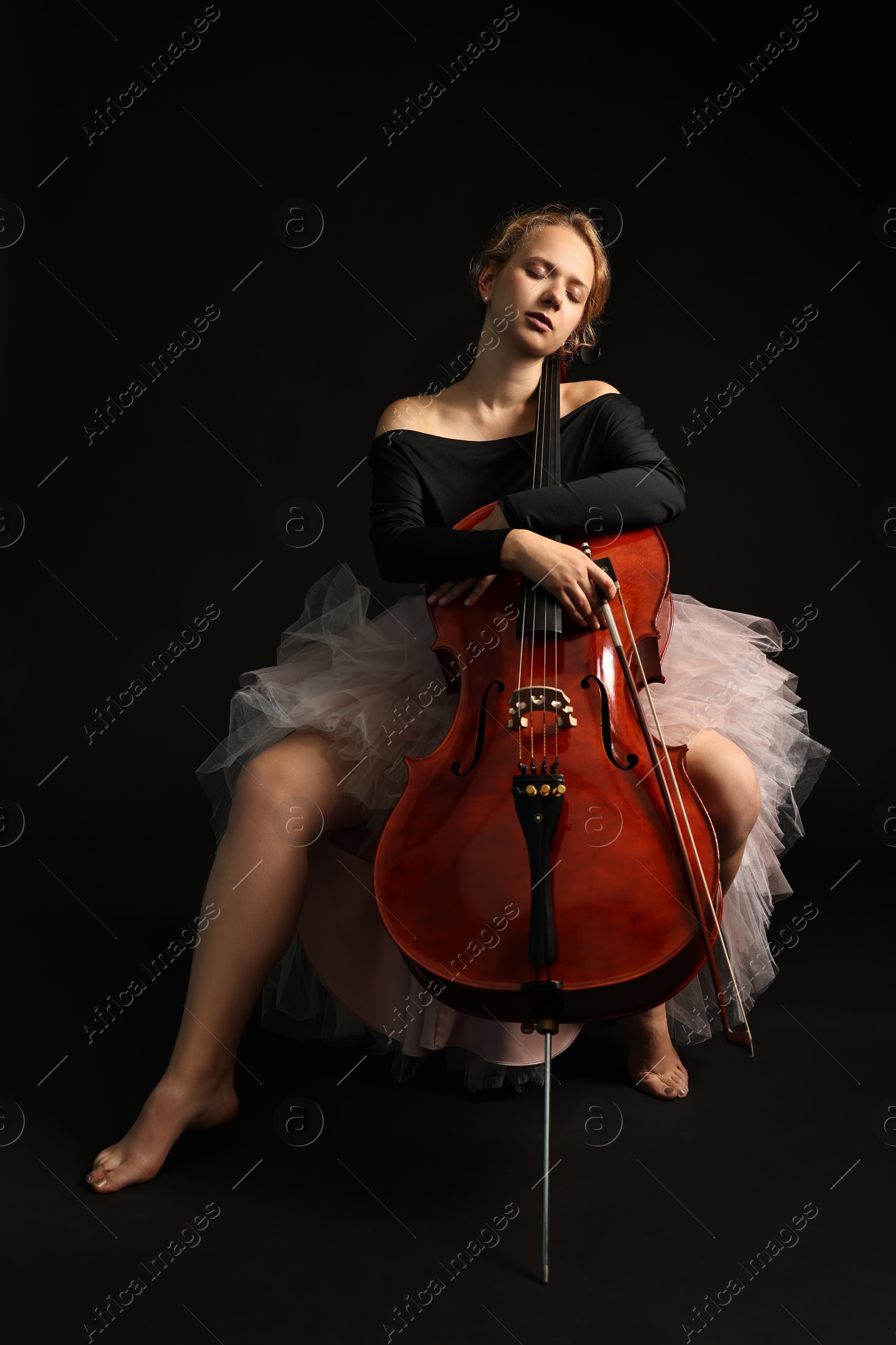 Photo of Beautiful young woman with cello on black background