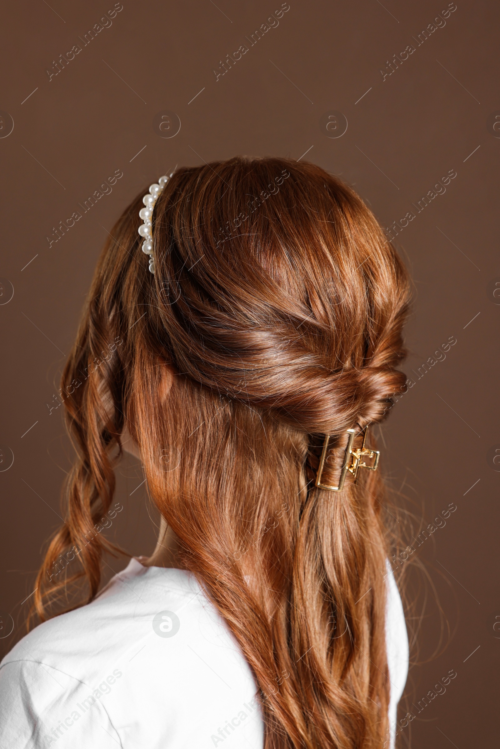 Photo of Teenage girl with stylish hair accessories on brown background, back view