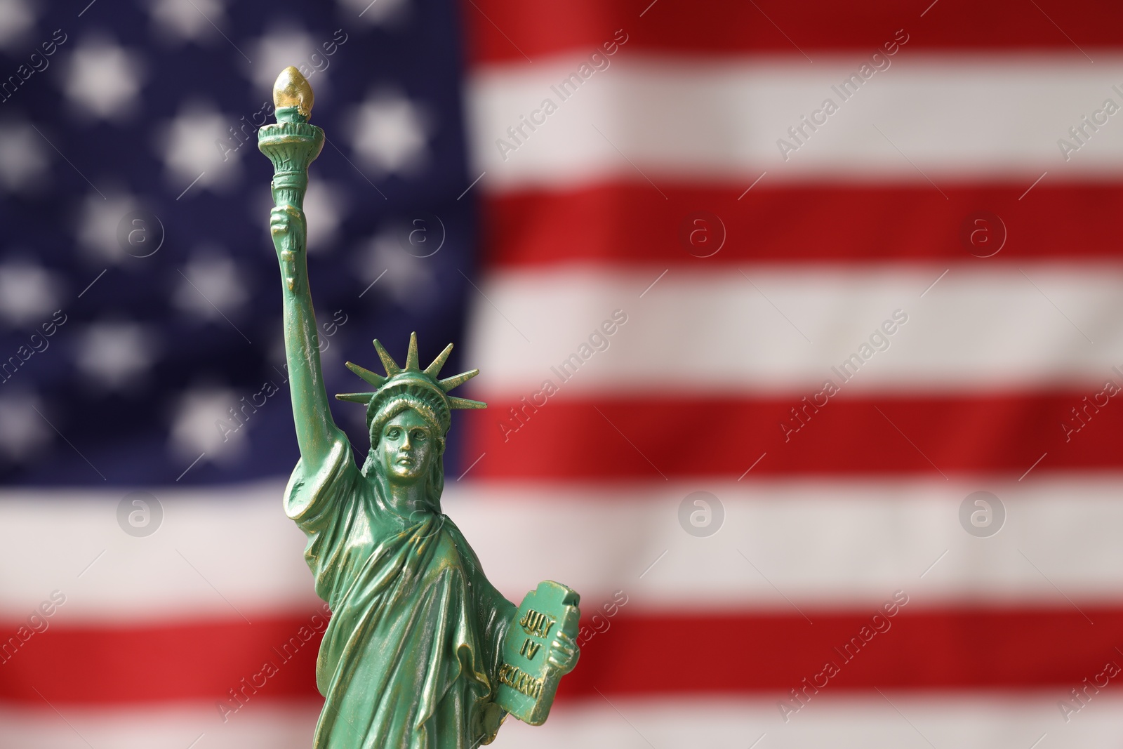 Photo of Statue of Liberty against flag of USA, closeup. Space for text