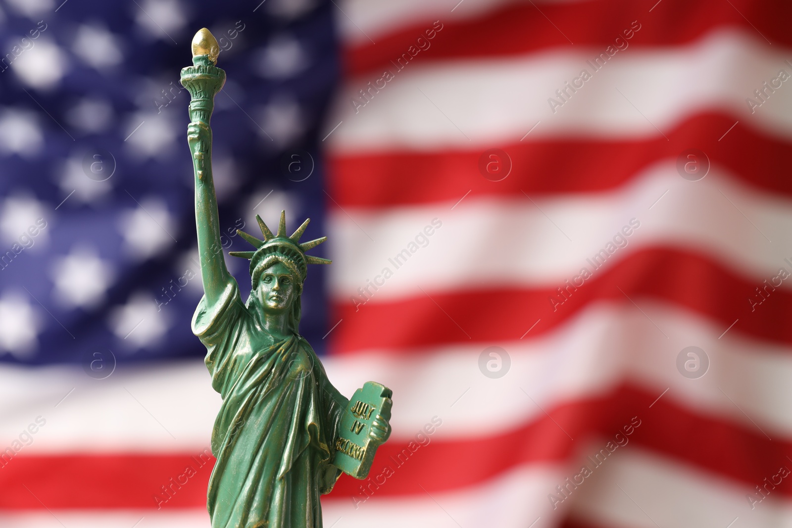 Photo of Statue of Liberty against flag of USA, closeup. Space for text