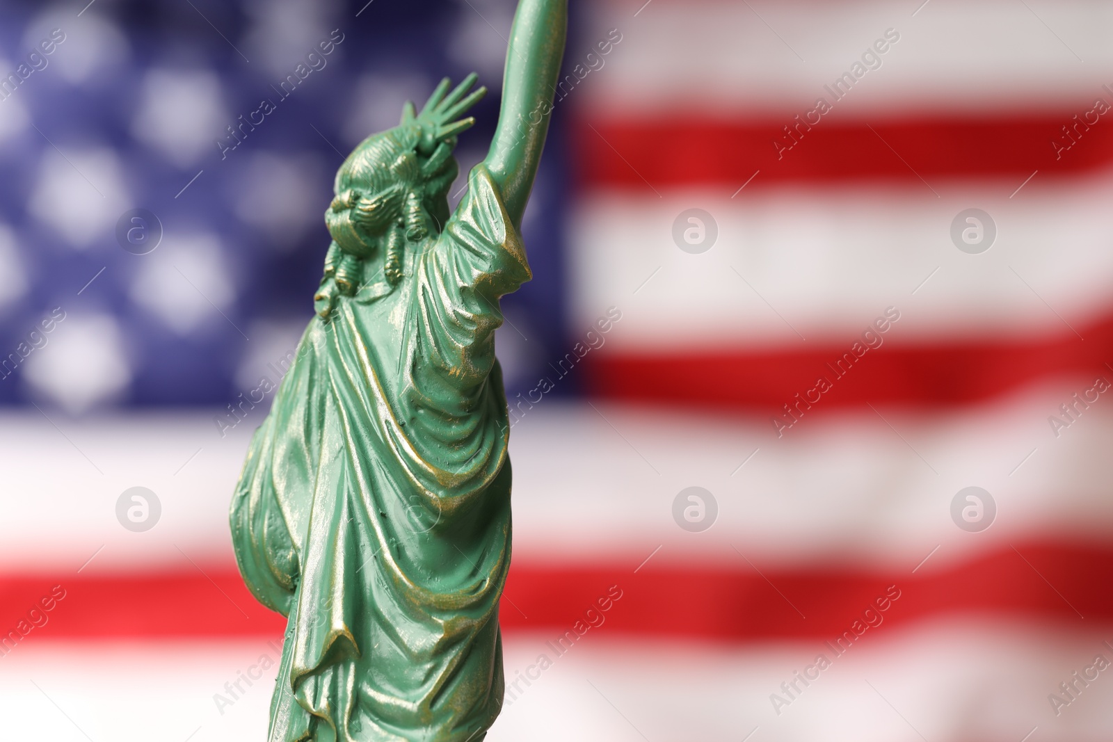 Photo of Statue of Liberty against flag of USA, closeup. Space for text