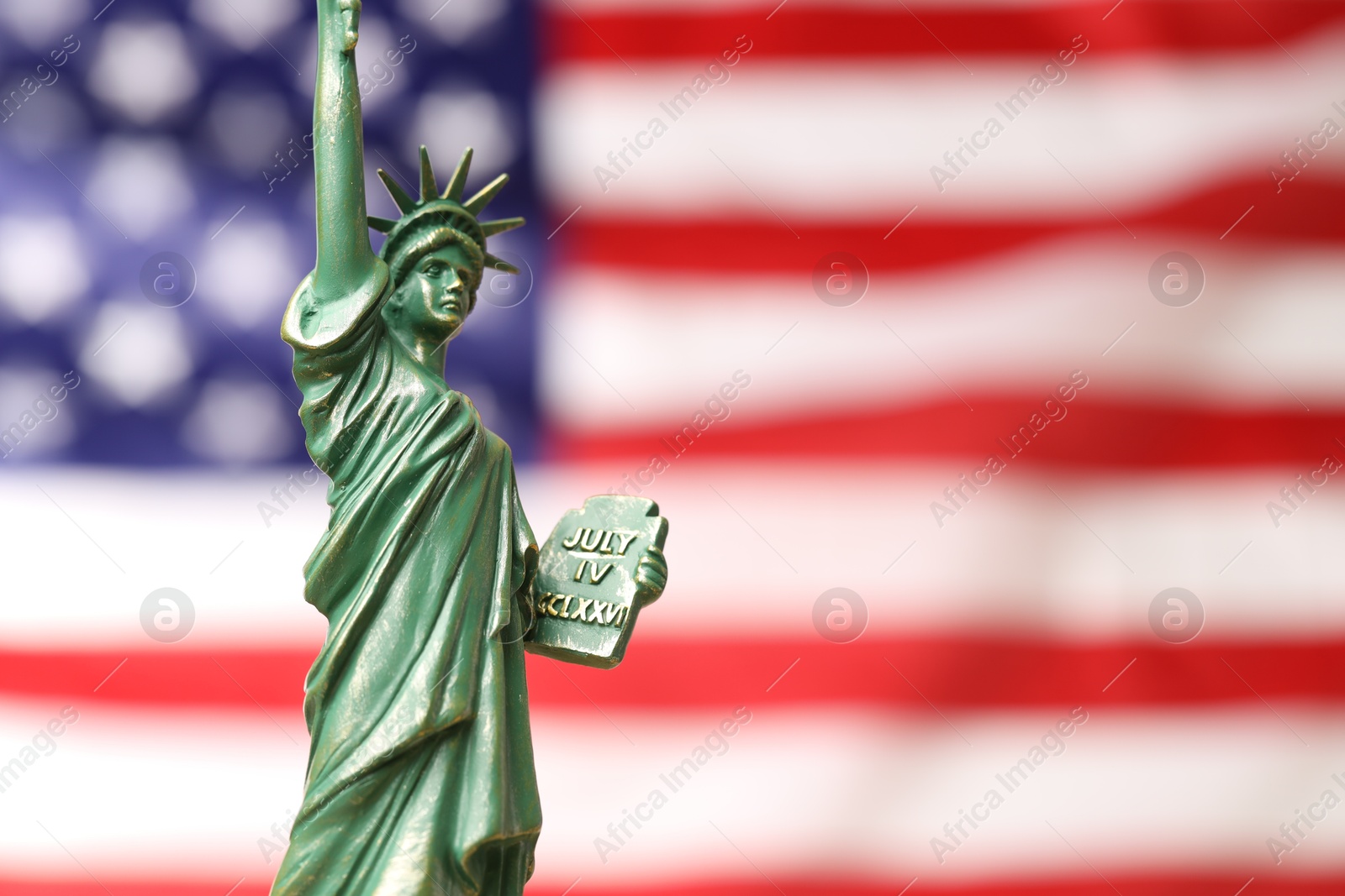 Photo of Statue of Liberty against flag of USA, closeup. Space for text