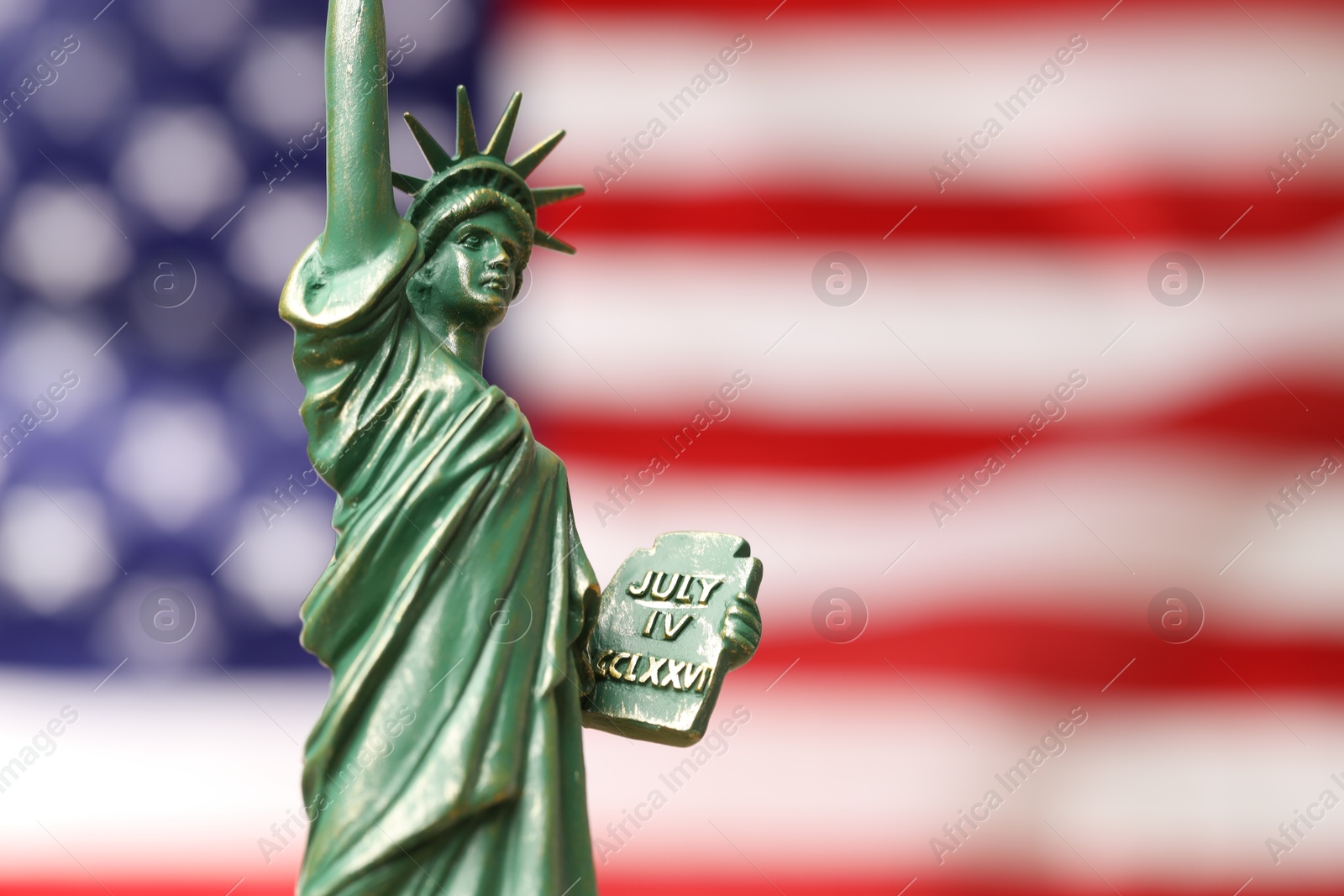 Photo of Statue of Liberty against flag of USA, closeup. Space for text