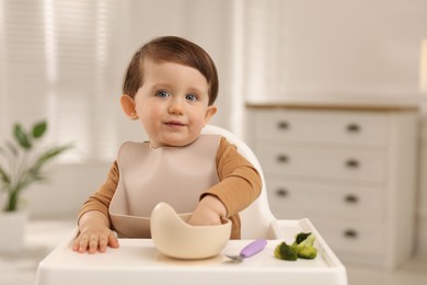 Photo of Cute little baby eating healthy food from bowl in high chair at home, space for text