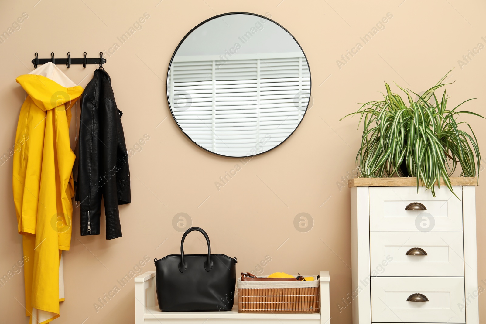 Photo of Coat rack with clothes, mirror, shoe storage bench and chest of drawers in hallway. Interior design