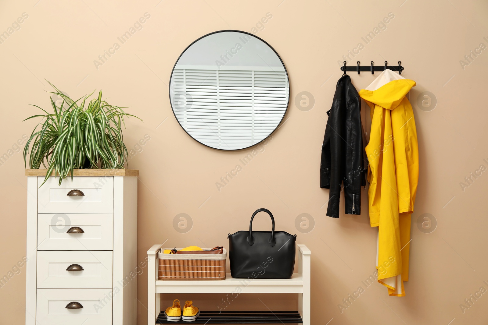 Photo of Coat rack with clothes, mirror, shoe storage bench and chest of drawers in hallway. Interior design