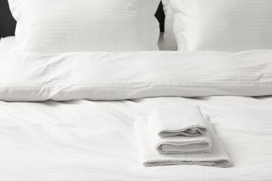 Photo of Bed with clean linens, pillows and towels indoors